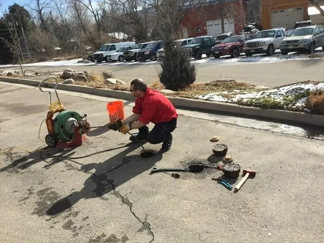 Worker performing drain cleaning