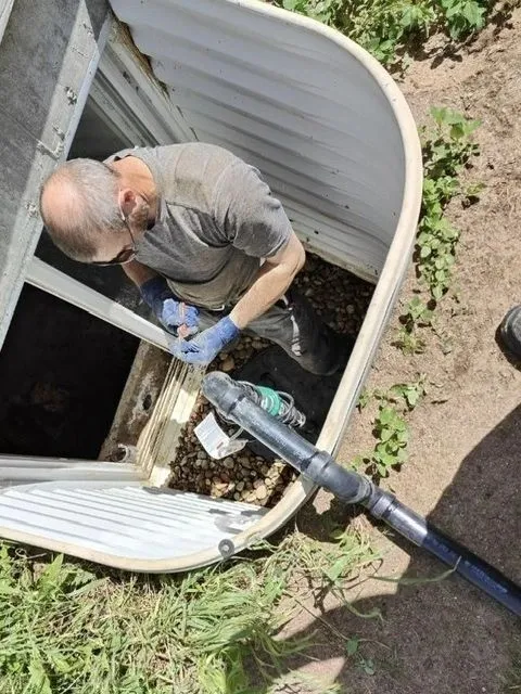 Serviceman in basement window well repairing plumbing