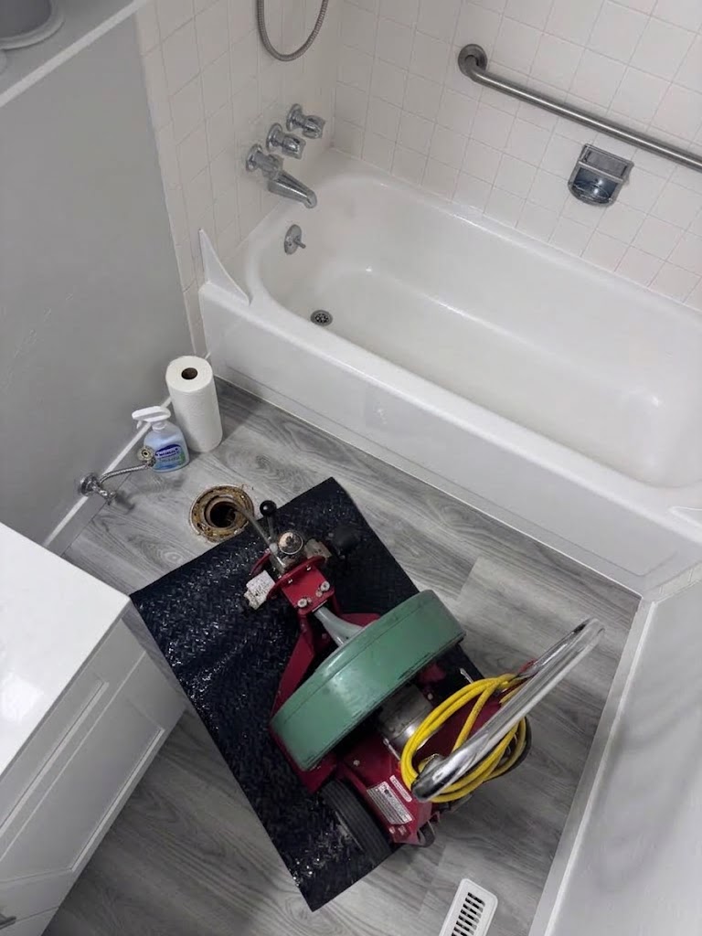 Plumber performing bathroom drain cleaning, clearing a clogged sink or tub drain to restore water flow