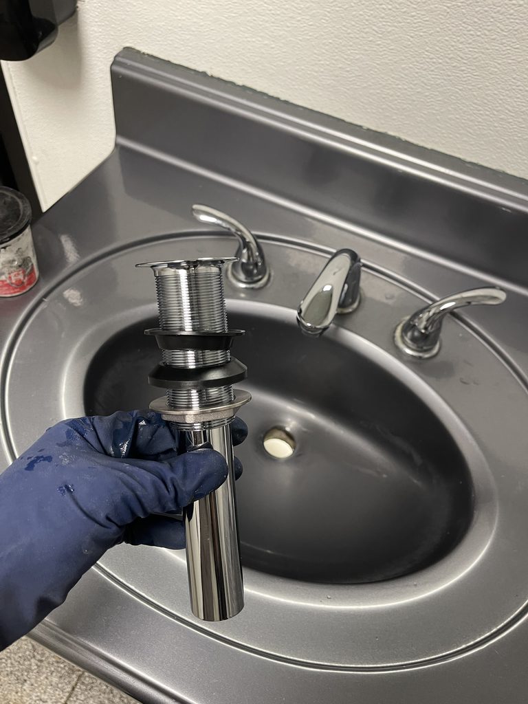 Plumber installing a new bathroom sink faucet and connecting supply lines during a fixture upgrade