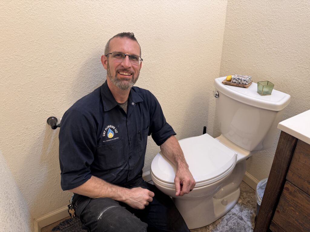 Gabriel performing a bathroom toilet repair, inspecting internal tank components to fix a running or clogged toilet